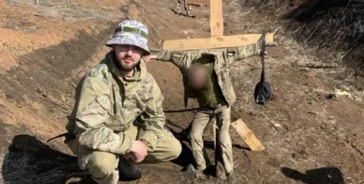 Фото УП. Владислав Пастух фотографується на тлі прив'язаного до хреста військового